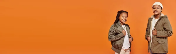 Jolly africano americano ragazzo e ragazza in caldi abiti sorridente a macchina fotografica su sfondo arancione, banner — Foto stock