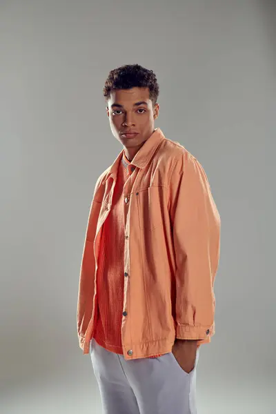Stylischer Mann im pfirsichfarbenen Hemd steht vor grauer Wand und zeigt seinen makellosen Sinn für Mode — Stockfoto