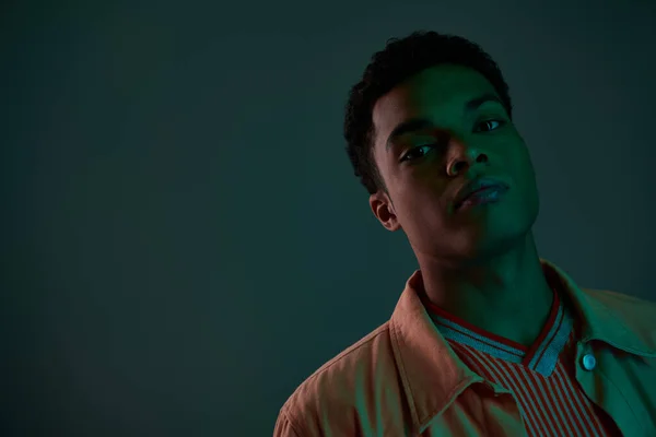 Schöner afrikanisch-amerikanischer Mann im Hemd blickt im dunklen Studio mit grünem Licht in die Kamera — Stockfoto