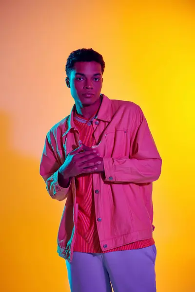 Homem elegante em pé na camisa rosa com as mãos dobradas, exalando confiança no fundo colorido — Fotografia de Stock