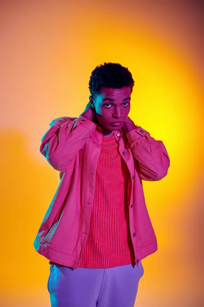 Young african american model posing in trendy and casual clothing with vibrant gradient background — Stock Photo