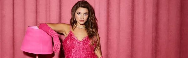 Giovane donna riccia in abito rosa piumato e guanti appoggiati sulla lampada da terra in camera glamour, banner — Foto stock