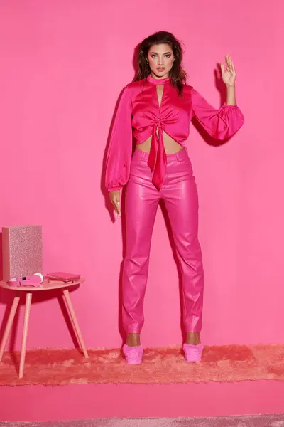Séduisante jeune femme en crop top et pantalon rose gesticulant anormalement et agissant comme une poupée — Photo de stock