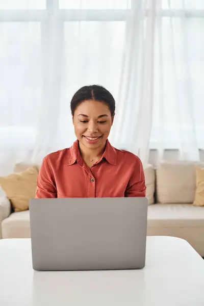Satisfied african american nutritionist using laptop while working remotely from her kitchen — Stock Photo