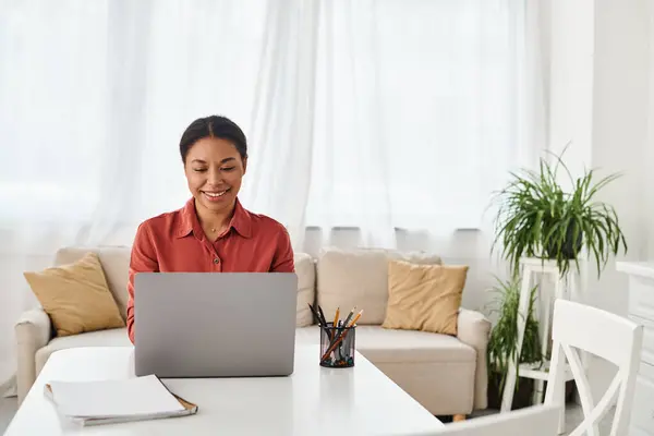 Щаслива афроамериканська жінка використовує ноутбук під час роботи з її сучасною кухнею, дієтолог — стокове фото