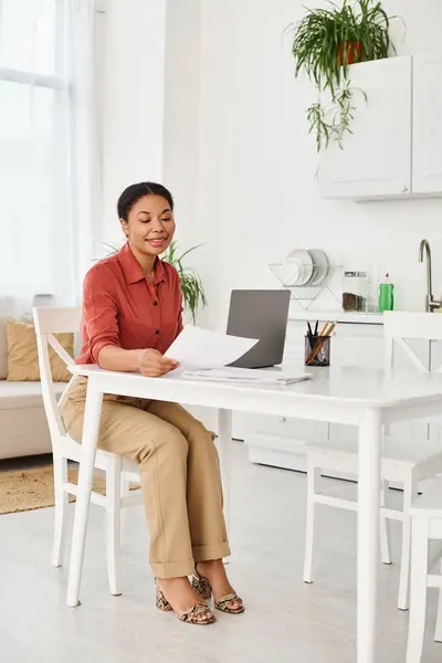 Счастливый африканский американский диетолог просматривает документы рядом с ноутбуком для онлайн консультации на дому — стоковое фото