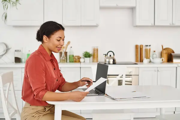 Cheerful african american nutritionist reviewing documents near laptop for online consultation — Stock Photo