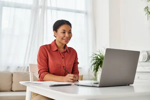 Pleased african american nutritionist taking notes during online consultation on laptop — Stock Photo