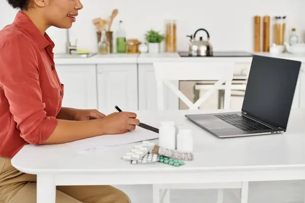 Cropped nutritionist writing prescription near medication during online consultation on laptop — Stock Photo