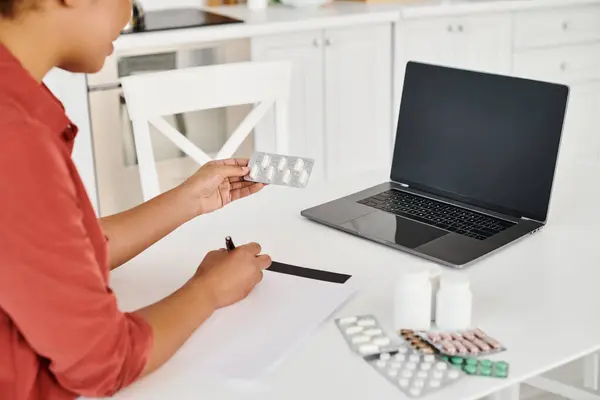 Cropped nutritionist writing prescription near medication during online consultation on laptop — Stock Photo