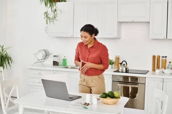 African american dietitian gesturing while standing near laptop and offering diet advice online — Stock Photo