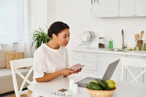 Happy african american nutritionist with pills looking at laptop during an online consultation — Stock Photo