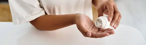 Colto afro-americano dietista versando pillole nel palmo della mano dal flacone dei farmaci, banner — Foto stock