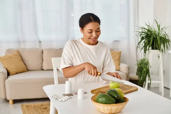 Nutricionista afro-americano feliz compara suplementos com frutas para uma dieta saudável em casa — Fotografia de Stock