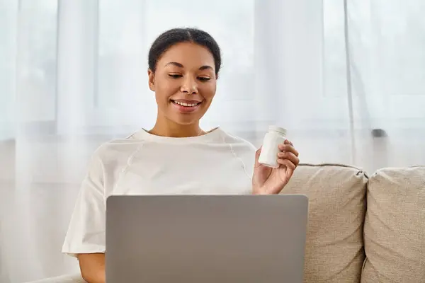 Allegro nutrizionista afro-americano con integratori che danno consigli dietetici via laptop in soggiorno — Foto stock