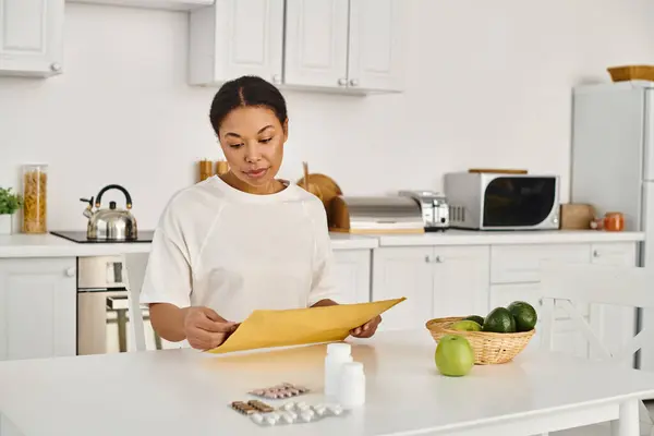 Brünette afrikanisch-amerikanische Frau öffnet Umschlag mit Ernährungsplan in der Nähe von Nahrungsergänzungsmitteln und Früchten — Stockfoto