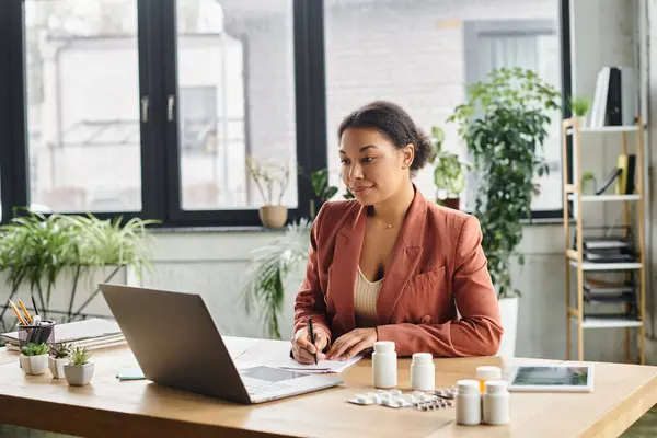 Curly african american nutritionist taking notes for an online session in a modern workspace — Stock Photo
