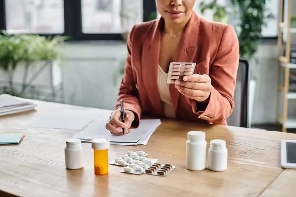 Cropped view of african american nutritionist checking medication and taking notes in office — Stock Photo