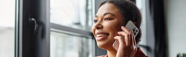 Щасливий афроамериканський дієтолог дає консультацію через смартфон у яскравому офісі, банер — стокове фото