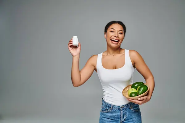 Dietista afroamericano feliz con frutas verdes y suplementos que muestran un estilo de vida saludable - foto de stock