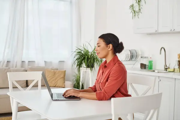 Smiling african american dietitian using her laptop while typing and working from home — Stock Photo