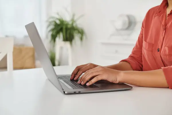 Foto recortada de dietista afroamericana usando su computadora portátil mientras escribe y trabaja desde casa - foto de stock