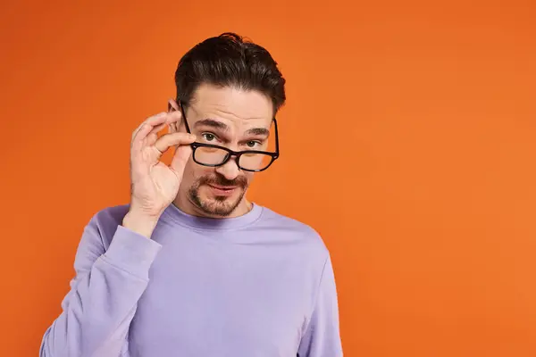 Bärtiger Mann im lila Sweatshirt mit Brille auf orangefarbenem Hintergrund, Modetrends — Stockfoto