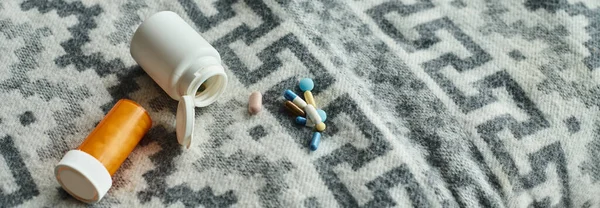 Diferentes medicamentos en manta gris con adorno, pastillas cerca de botellas de medicamentos de plástico, pancarta - foto de stock