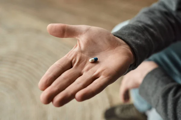 Vue recadrée de l'homme tenant la capsule bleue et blanche, photo rapprochée de la médication dans la main masculine — Photo de stock