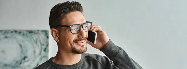 Bearded man in eyeglasses and grey jumper talking on smartphone in bedroom, phone call banner — Stock Photo