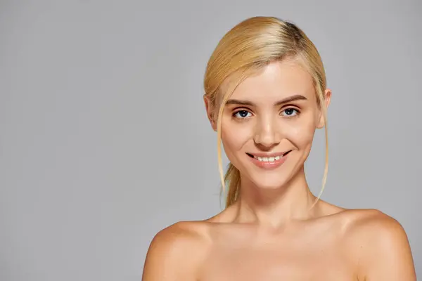 Beauty young woman with grey eyes looking forward and smiling broadly against in gray background — Stock Photo