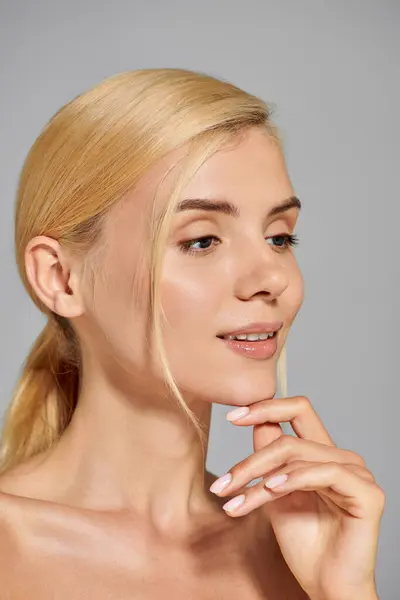 Beautiful young adult woman profile smiling calmly and touching chin in gray background — Stock Photo