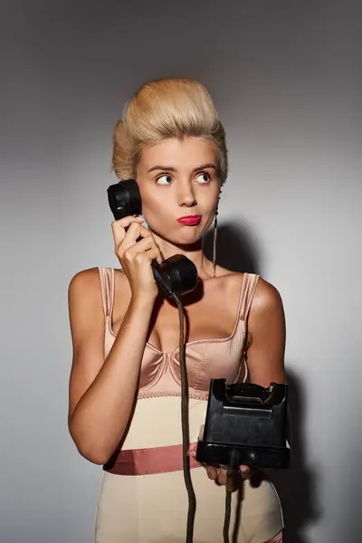 Charming young woman with red lipstick puzzled conversation on retro phone in grey background — Stock Photo