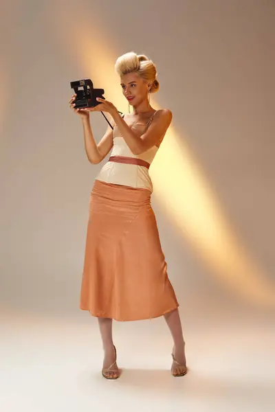 Chica con estilo en sus años 20 en traje de corsé tomar fotos con cámara retro en fondo gris - foto de stock
