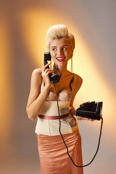 Attractive young woman with red lips talking and smiling on retro phone against gray background — Stock Photo