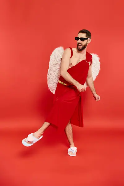 Piena lunghezza dell'uomo barbuto eccitato in costume cubico che balla su rosso, festa di San Valentino — Foto stock