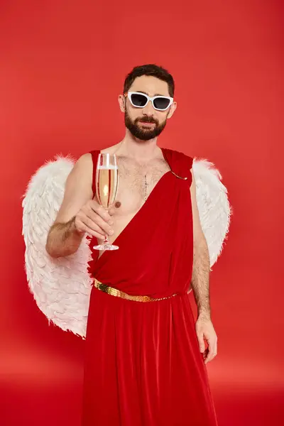 Uomo barbuto in occhiali da sole e cupido costume brindare con champagne in rosso, San Valentino — Foto stock