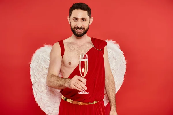Homme barbu gai en costume de Cupidon et ailes toasting avec champagne sur le rouge, st Saint-Valentin — Photo de stock