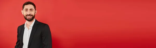Retrato de hombre barbudo alegre en traje de desgaste formal sonriendo a la cámara en la bandera roja, horizontal - foto de stock