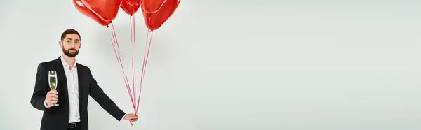 Stylish bearded man with red heart-shaped balloons and champagne glass on grey, horizontal banner — Stock Photo