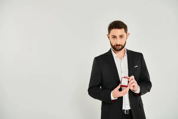 Confiante empresário bem sucedido mostrando caixa de jóias como dia de São Valentim presente no cinza — Fotografia de Stock