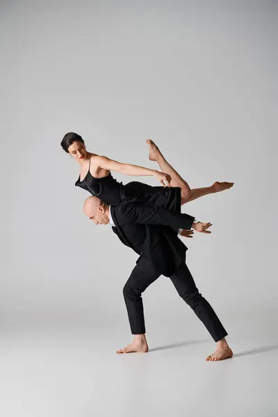 Graciosa dança, jovem casal realizando uma rotina acrobática em um cenário de estúdio com fundo cinza — Fotografia de Stock
