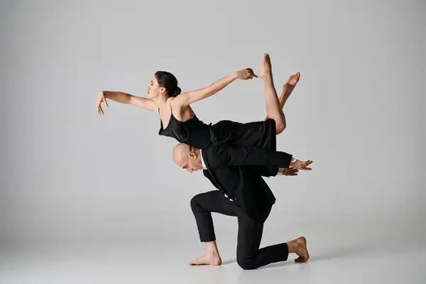 Baile elegante, pareja joven realizando una rutina acrobática en un estudio con fondo gris - foto de stock
