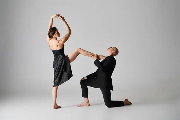 Baile elegante de pareja joven actuando juntos en un estudio con fondo gris - foto de stock