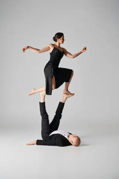 Dynamic duo, couple of acrobats performing balance act in a studio setting with grey background — Stock Photo