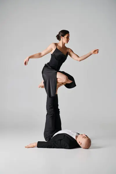 Dúo dinámico, pareja de acróbatas que realizan el acto de equilibrio en un entorno de estudio con fondo gris - foto de stock