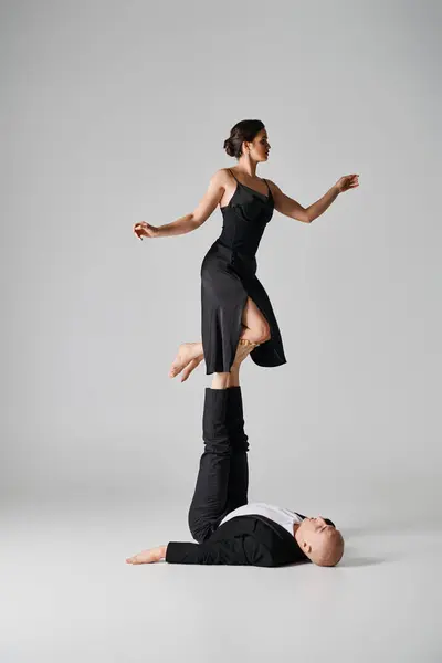 Duo atlético, casal de acrobatas realizando ato de equilíbrio em um cenário de estúdio com fundo cinza — Fotografia de Stock