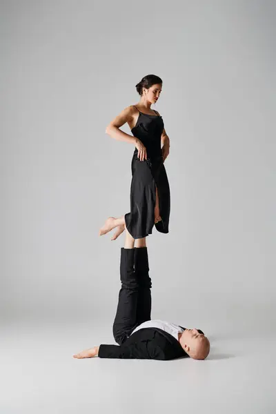 Duo atlético, casal de acrobatas realizando ato de equilíbrio em um ambiente de estúdio com fundo cinza — Fotografia de Stock