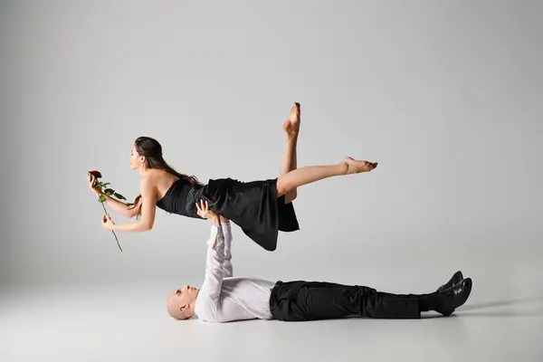 Dancer lying on the floor and lifting body of woman with red rose during dance performance — Stock Photo