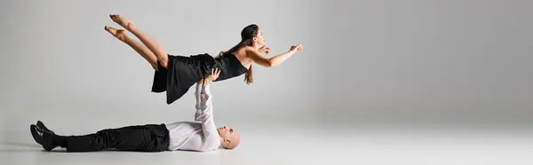 Мужчина танцор лежит на полу и поднимает тело женщины в платье во время танцевального представления, баннер — стоковое фото